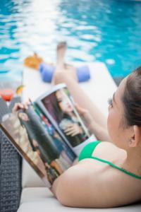 金瓯金瓯省孟清豪华酒店的一个穿着比基尼的女人在游泳池旁读杂志