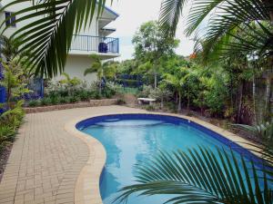麦凯Mackay Seabreeze Apartments的一座树木繁茂的房屋前的游泳池