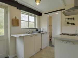 博德明The Old Engine House的厨房配有白色橱柜、水槽和窗户。
