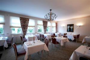 黑尔姆施泰特赫尔姆施泰特公园酒店的餐厅配有白色的桌椅和吊灯