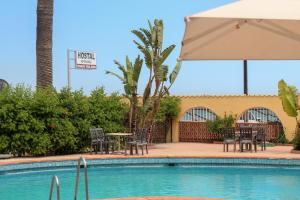 贝纳哈拉菲埃斯佩兰萨旅馆的一个带椅子和桌子的游泳池以及一把遮阳伞
