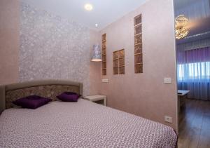 文茨皮尔斯Poruka apartamenti的一间卧室配有一张带紫色枕头的床