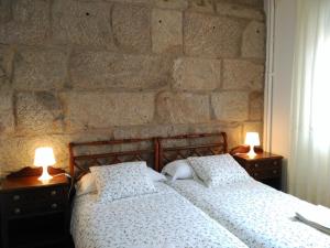 贡多马尔A casa de Carmiña的一间卧室设有石墙、两张床和灯。