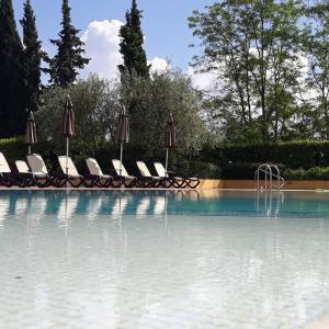 蒙特卡洛La Torre wine resort的一个带椅子和遮阳伞的游泳池和一个游泳池