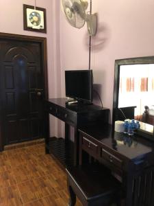 万荣索泰餐厅旅馆的客房设有一张带电视和镜子的书桌