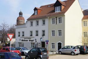 格尔利茨Goldener Engel /Pension的一座白色的建筑,前面有汽车停放