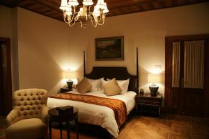上海衡山马勒别墅饭店的一间卧室配有一张床、一把椅子和一个吊灯。