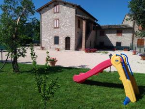 阿西西Agriturismo"Il Sagrato di Assisi" appartamenti,camere的房子前面的草上滑着滑梯
