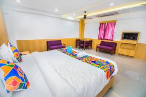 钦奈FabExpress Picnic Plaza Mylapore的一间卧室配有一张大床和两张紫色椅子