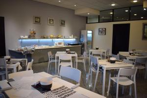 阿尔巴·阿德里亚蒂卡巴佛罗索酒店的餐厅设有白色的桌椅和柜台