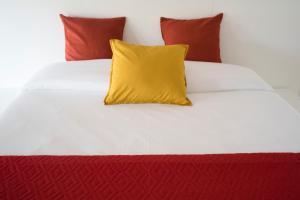 帕埃塞Relais Officina del Tempo的白色床上的黄色枕头和红色枕头