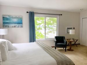 Hubbard LakeChurchill Pointe Inn的卧室配有床、椅子和窗户。