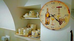 洛科罗通多Trullo Sereno Angelo的架子上的时钟,上面有杯子和一瓶葡萄酒