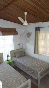 Rodrigues IslandLe Paradiso Apartments的一间卧室配有两张床和吊扇