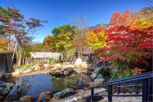 高山Miyama Ouan Kyoritsu Resort的花园设有种有岩石和树木的池塘