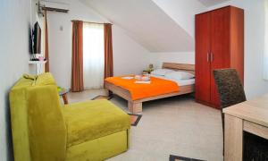 蒂瓦特Apartmani Bekonja的一间卧室配有一张床和一张黄色椅子