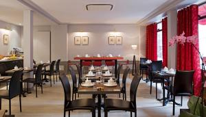 巴黎杜尔那马莱酒店的餐厅设有木桌和椅子以及红色窗帘