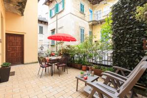 奥尔塔圣朱利奥Appartamenti Orta的庭院配有椅子和一张桌子及红伞