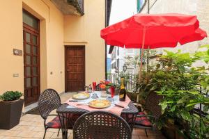 奥尔塔圣朱利奥Appartamenti Orta的露台上的一张桌子和一把红色遮阳伞