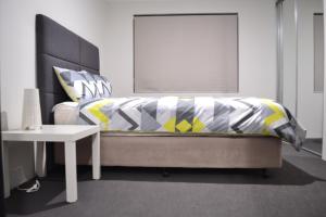 珀斯Perth Urban Lodge的一间卧室配有一张黄色和灰色的被子。