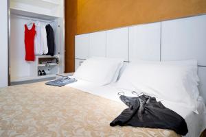 里米尼氛围套房酒店的一间卧室配有白色床单和红色连衣裙