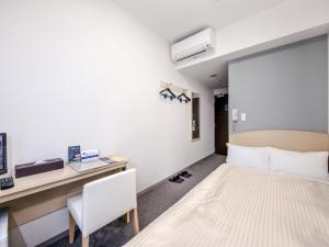 盛冈盛冈乌尼佐快速酒店的一间卧室配有一张床、一张桌子和一把椅子