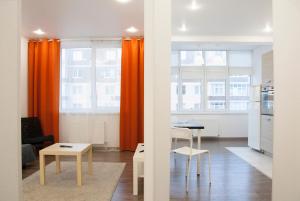 斯塔夫罗波尔Апартаменты В ЦЕНТРЕ ЖК "Шоколад"的客厅配有橙色窗帘和桌椅