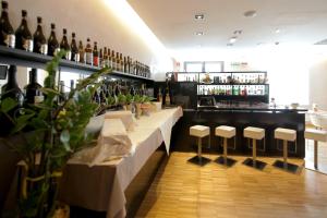 龙基德伊莱焦纳里梅杰酒店的酒吧,酒吧里摆放着一排凳子和瓶装葡萄酒