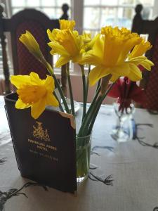 EdzellThe Panmure Arms Hotel的一张纸片桌子上的一个黄色花瓶