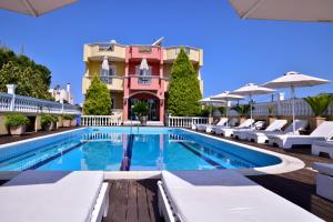 路特奇克里斯蒂娜马里斯酒店的一座带白色躺椅的游泳池和一座建筑