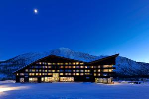 米尔克河谷Myrkdalen Resort Hotel的雪中与天空中的月亮相隔的建筑