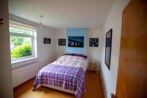 牛顿斯图尔特Kelpies Cottage的一间卧室配有一张带铺着地毯的床和窗户。