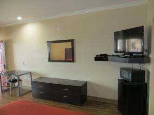 休斯顿Palace Inn Westheimer的客厅设有壁挂式电视和桌子。