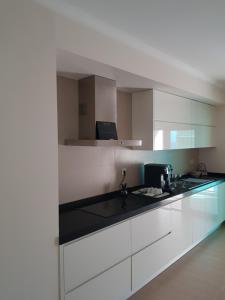 波尔蒂芒Rocha Prime - Standing apartment T3的厨房配有白色橱柜和黑色台面