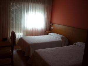 VimianzoPensión Risco的酒店客房设有两张床和窗户。