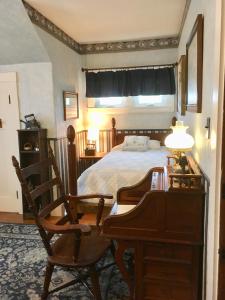 CaribouOld Iron Inn Bed and Breakfast的一间卧室配有一张床、一张桌子和一把椅子