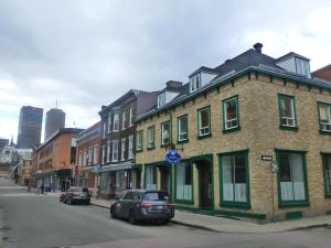 魁北克市EKONO HOSTEL LA BELLE PLANETE BACKPACKERS Downtown Quebec City的城市街道上的砖砌建筑,有车辆停放