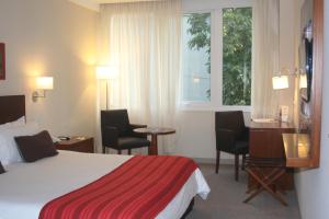 耶尔瓦布埃纳Howard Johnson Hotel Yerba Buena的配有一张床、一张书桌和一扇窗户的酒店客房