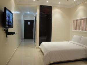 科威特Marina Royal Hotel Suites的一间卧室配有一张床和一台平面电视