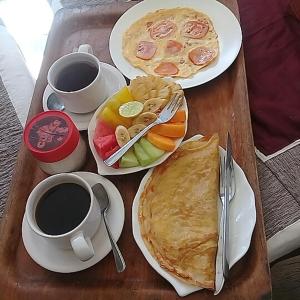 八丹拜Padangbai Beach inn的一张桌子,上面放着两盘食物和两杯咖啡