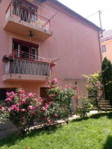 利夫诺Apartmani Konta的粉红色的房子,设有阳台和粉红色的鲜花