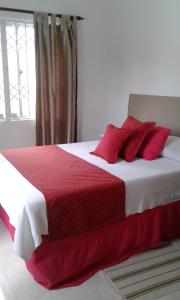 博瓦隆JB自助公寓的卧室配有红色和白色的床和红色枕头