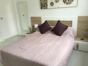 弗拉门卡海滩Boulevard La Zenia Villa的一间卧室配有一张大床,提供紫色床单和枕头