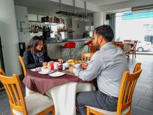 特鲁希略Libertad Hotel的坐在餐桌旁吃食物的男人和女人