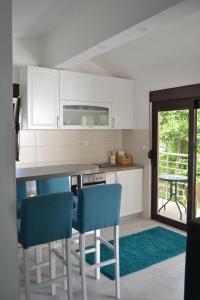 里桑Apartments Niković的厨房配有白色橱柜和蓝色椅子