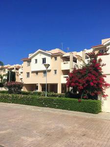 皮拉Pyla Village Resort F110 (Apartment near Larnaca)的一座白色的大建筑,前面有红花