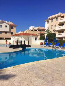 皮拉Pyla Village Resort F110 (Apartment near Larnaca)的一座带蓝色椅子的游泳池和一座建筑