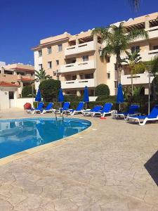 皮拉Pyla Village Resort F110 (Apartment near Larnaca)的一座带蓝色躺椅的游泳池和一座建筑