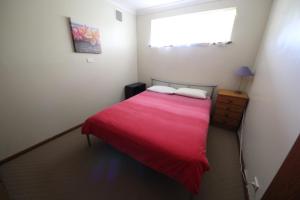 帽头镇Stouty's at Hat Head的一间卧室配有一张带红色毯子的床和窗户。