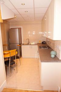 依尔福Home from Home的厨房配有白色橱柜、桌子和冰箱。